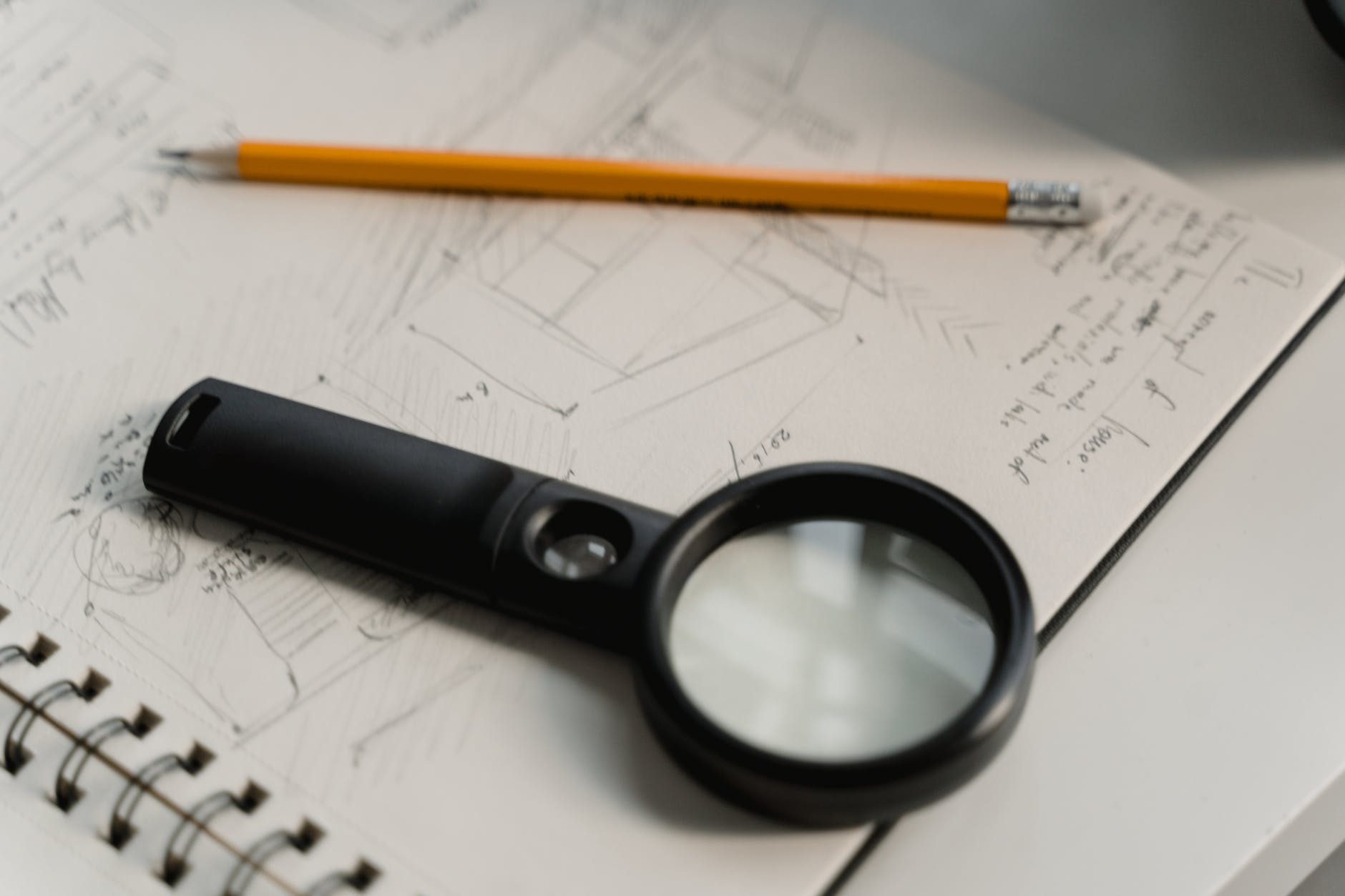 black magnifying glass beside yellow pencil