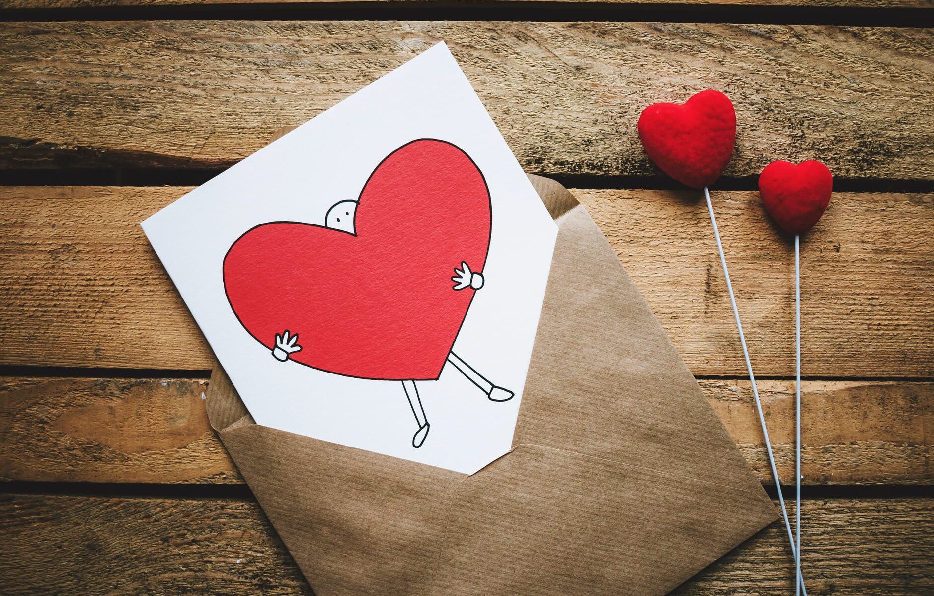 white black and red person carrying heart illustration in brown envelope