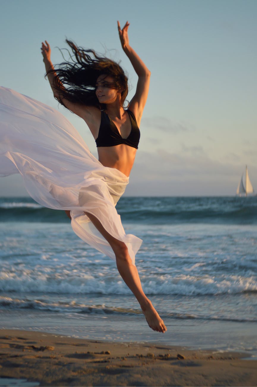 flexible dancer rehearsing on shore of ocean
