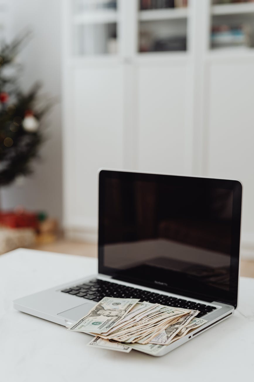 selective focus photo of a silver laptop with banknotes