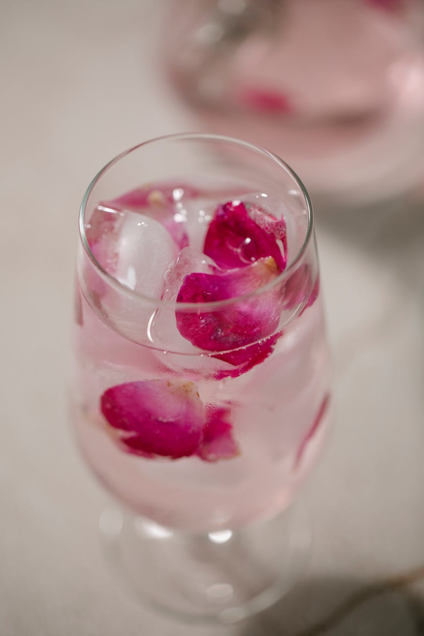 glass of cold iced water with rose petals