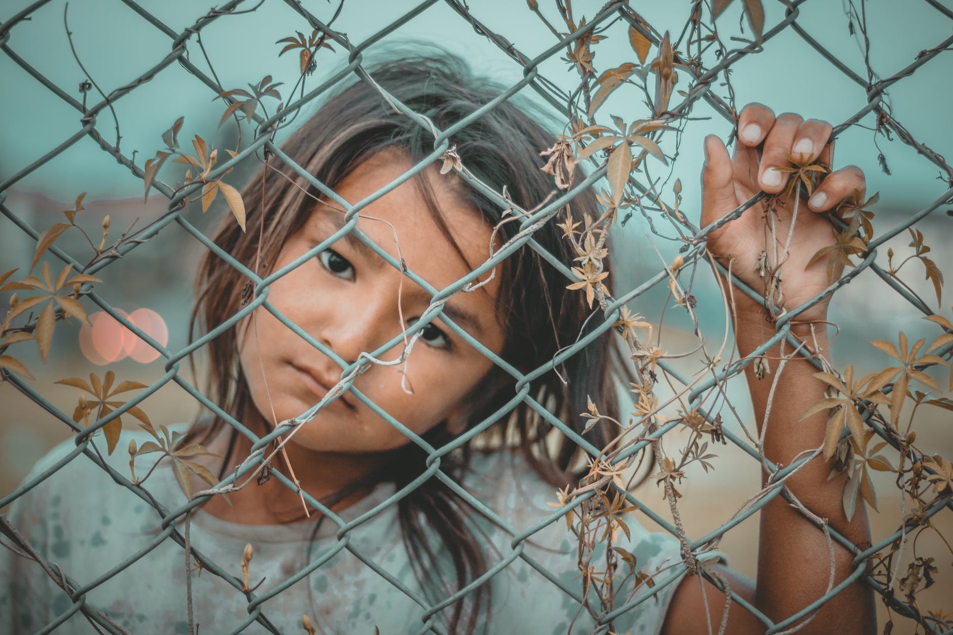 girl s white and gray crew neck top holding gray wire fence