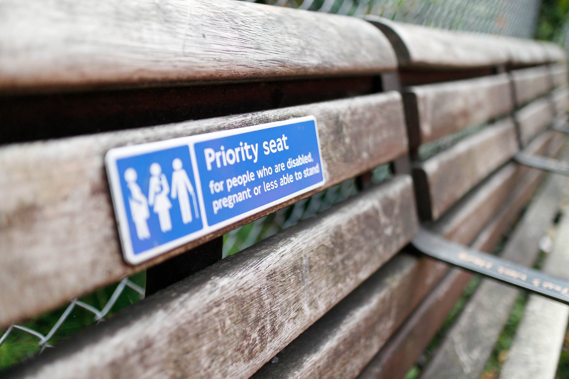 a wooden bench with priority seat signage