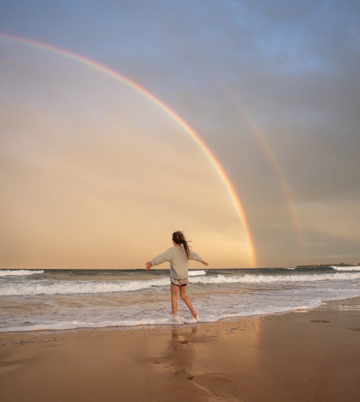 anonymous woman on beach with rainbow