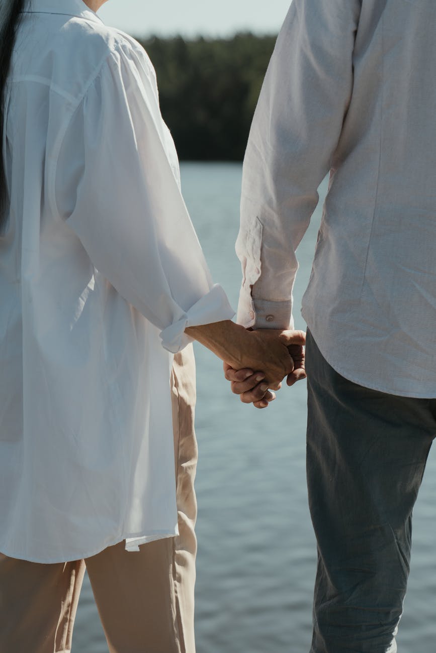 man in white dress shirt and black pants holding hands with woman in white long sleeve