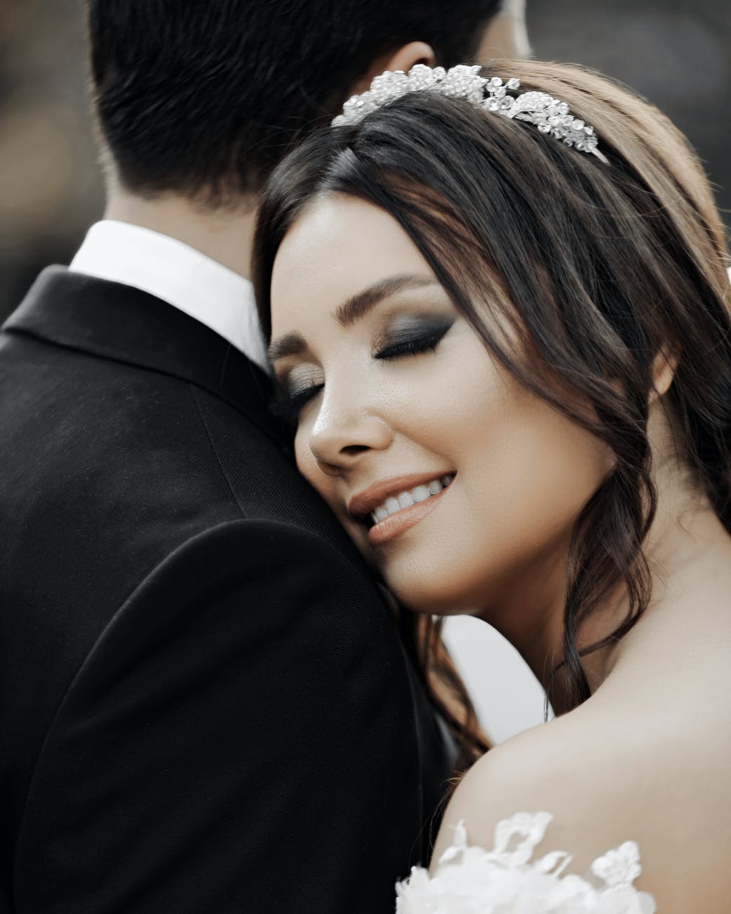close up of smiling bride with her eyes closed hugging groom
