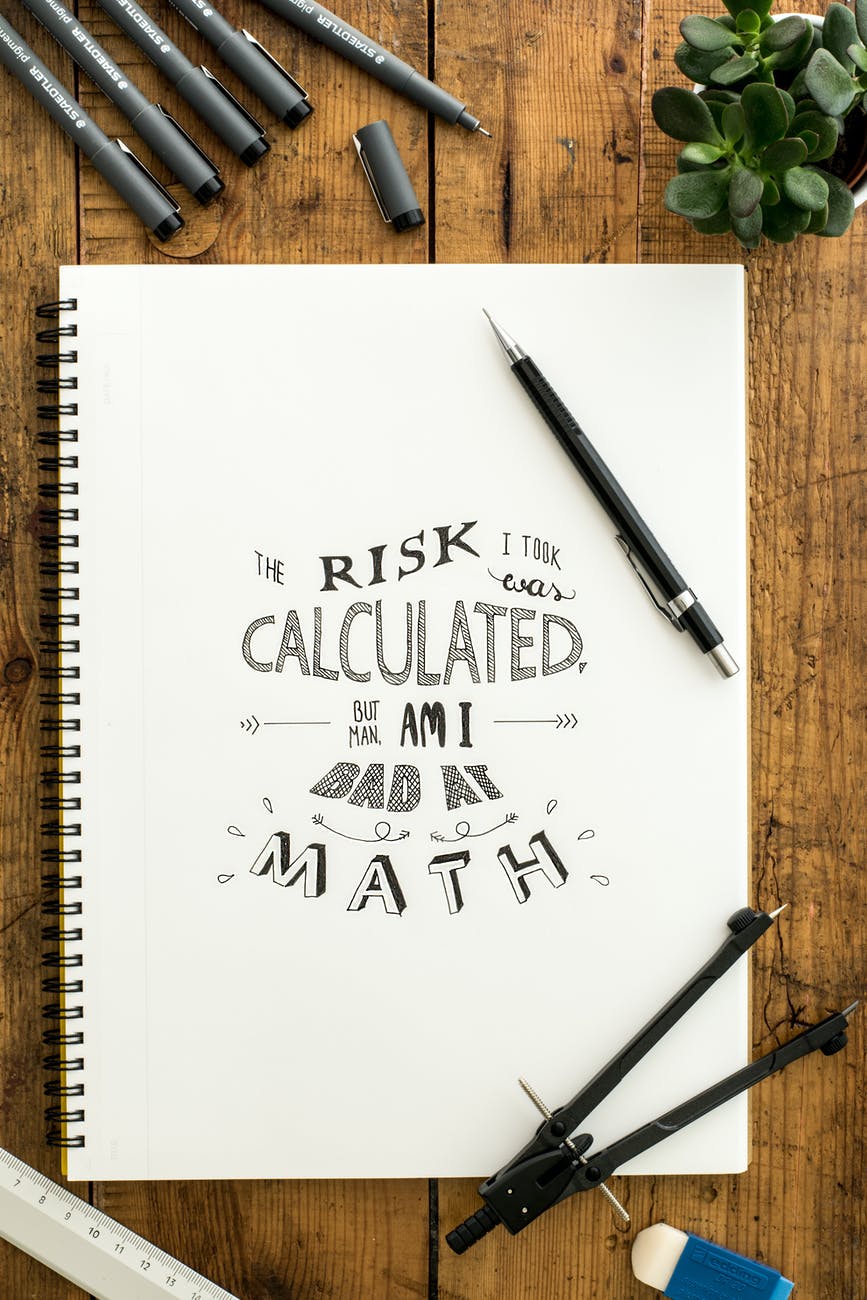 flat lay photography of notebook pen and drafting compass