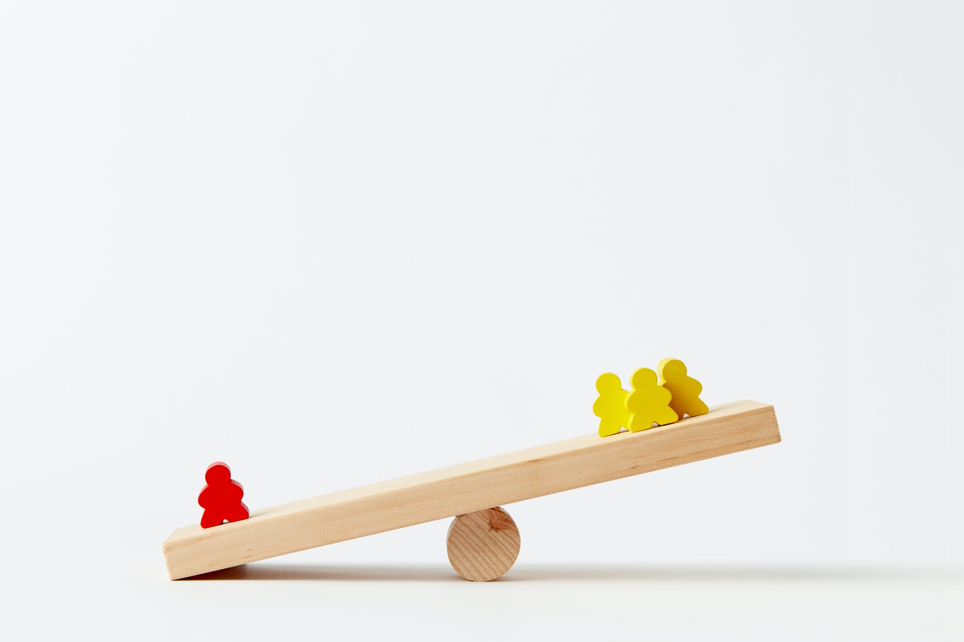 human shape blocks on wooden seesaw