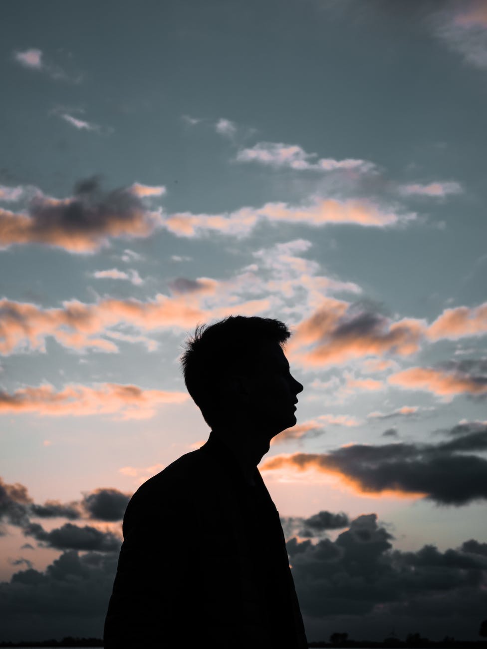 silhouette of man under cloudy sky