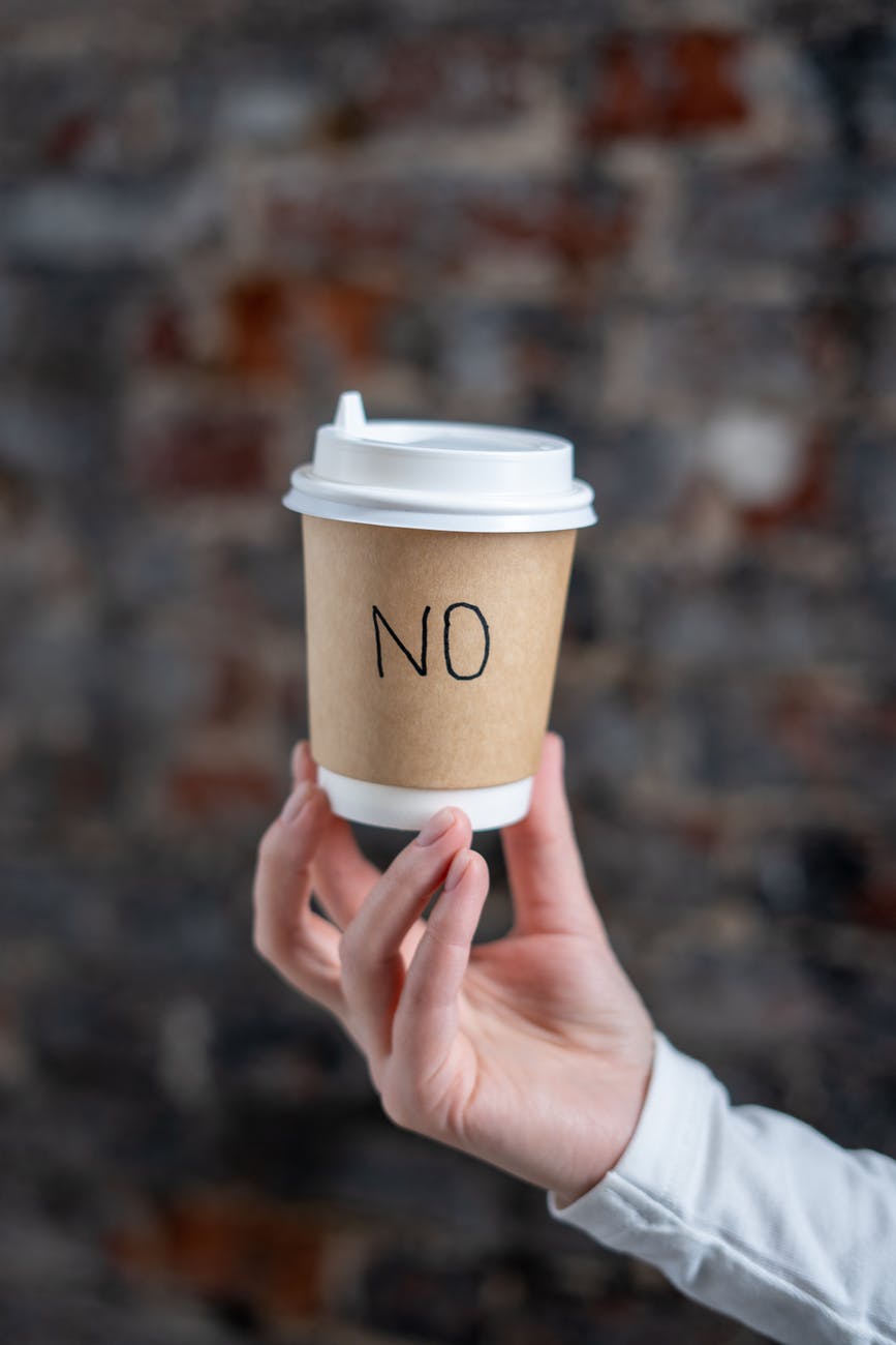 a person holding a paper cup with the word no
