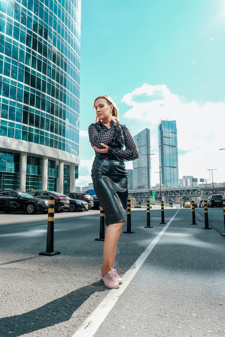 trendy woman standing near contemporary glass skyscrapers