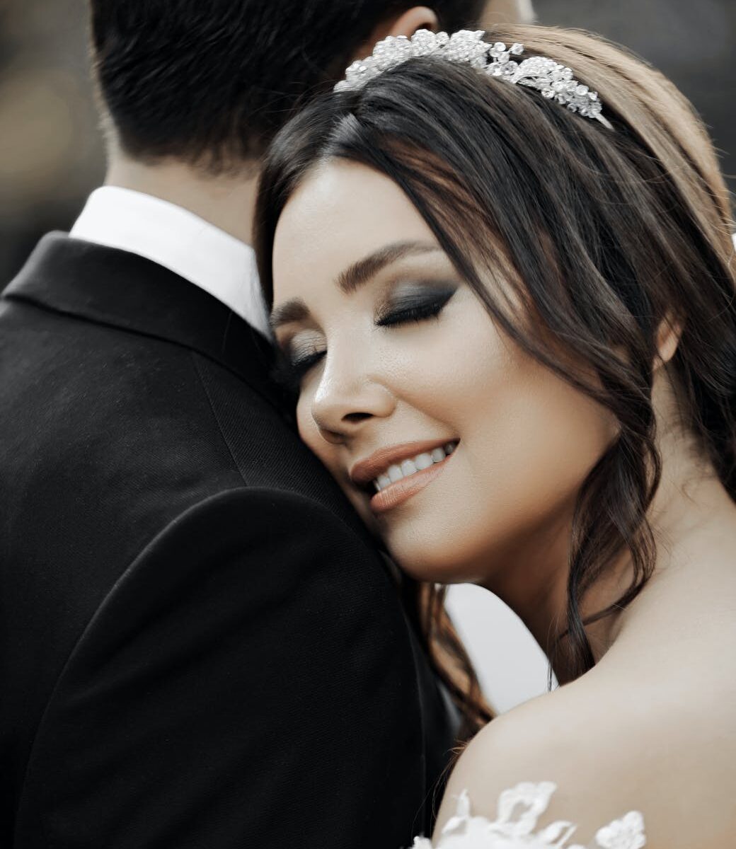 close up of smiling bride with her eyes closed hugging groom